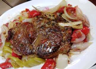 Καλοψημένη μοσχαρίσια μπριζόλα μέσα σε ανοιγμένη λαδόκολλα με μαλακά κρεμμύδια πιπεριές και φρέσκια ρίγανη