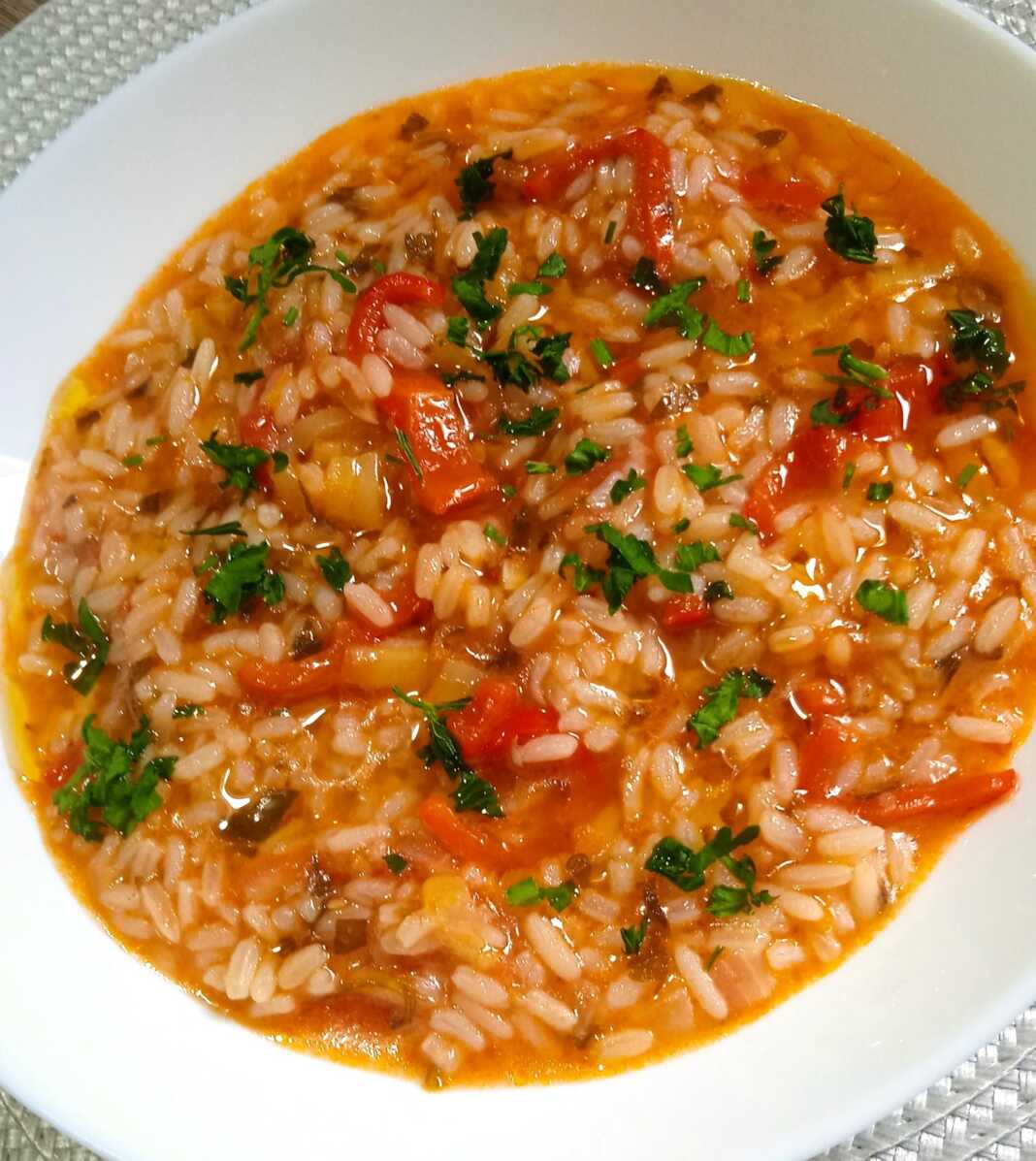 Ntomatorizo kalokairino Ένα πιάτο με ζεστό, κοκκινωπό ντοματόρυζο, πασπαλισμένο με ψιλοκομμένο πράσινο μαϊντανό, έτοιμο για σερβίρισμα.