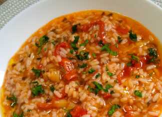 Ένα πιάτο με ζεστό, κοκκινωπό ντοματόρυζο, πασπαλισμένο με ψιλοκομμένο πράσινο μαϊντανό, έτοιμο για σερβίρισμα.