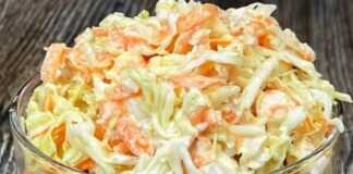 Μια λευκή σαλάτα σε ένα γυάλινο μπολ, που περιέχει ψιλοκομμένο λάχανο, τριμμένο καρότο και κομμάτια κοτόπουλου, ανακατεμένη με λεπτόλευκη σάλτσα.