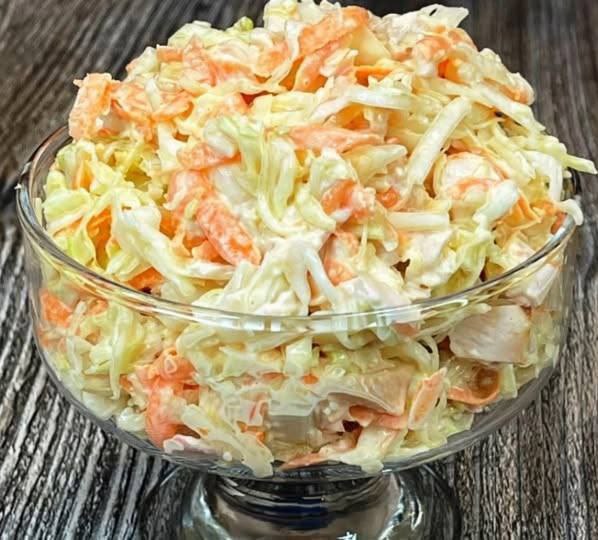 aspri salata Μια λευκή σαλάτα σε ένα γυάλινο μπολ, που περιέχει ψιλοκομμένο λάχανο, τριμμένο καρότο και κομμάτια κοτόπουλου, ανακατεμένη με λεπτόλευκη σάλτσα.