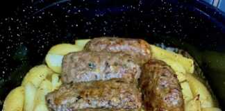 Ένα ταψί φούρνου γεμάτο με χρυσαφένια, ψημένα ρολάκια κιμά και κομμάτια πατάτας.