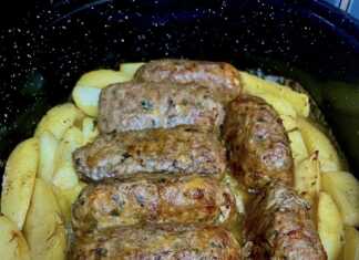 Ένα ταψί φούρνου γεμάτο με χρυσαφένια, ψημένα ρολάκια κιμά και κομμάτια πατάτας.