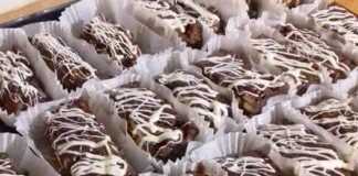 Ατομικός Κορμός / Μωσαϊκό (χωρίς ψήσιμο!) Ένα πιάτο γεμάτο με τετράγωνα κομμάτια σκούρου σοκολατένιου κορμού με μπισκότα, στολισμένα με λευκές γραμμές λιωμένης σοκολάτας.