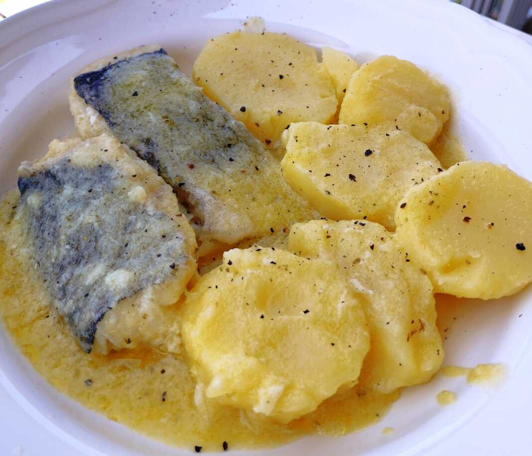 Ένα πιάτο με ένα κομμάτι ψάρι (μπακαλιάρο) και χοντρές ροδέλες πατάτας, περιχυμένα με μια πηχτή, λευκή, λεμονάτη σάλτσα.