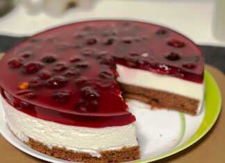 Μία τούρτα από πολύστρωτο cheese κέικ με βάση σοκολατένιου παντεσπανι λευκή κρεμώδη μους τυριού και κόκκινη στρώση ζελέ με ολόκληρα κεράσια.