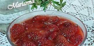 Ενα μπολ με στρώσεις cheesecake, που δείχνουν μια βάση από μπισκότα, μια λευκή κρεμώδη στρώση και κόκκινες φράουλες με σιρόπι στην κορυφή.