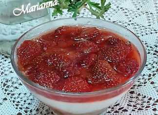 Ενα μπολ με στρώσεις cheesecake, που δείχνουν μια βάση από μπισκότα, μια λευκή κρεμώδη στρώση και κόκκινες φράουλες με σιρόπι στην κορυφή.