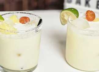 Δύο ποτήρια με δροσερό αναψυκτικό με ανανά και καρύδα, γεμάτο παγάκια, κομμάτια ανανά, και διακοσμημένο με ένα κεράσι και τριμμένη καρύδα στο χείλος.