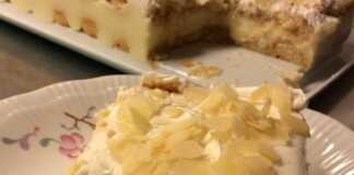 Ένα κομματι γλυκό που δείχνει στρώσεις από μπισκότα σαβαγιάρ, λευκή κρέμα και σαντιγί, πασπαλισμένο με καφέ φιλέ αμυγδάλου.