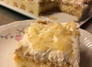 Ένα κομματι γλυκό που δείχνει στρώσεις από μπισκότα σαβαγιάρ, λευκή κρέμα και σαντιγί, πασπαλισμένο με καφέ φιλέ αμυγδάλου.