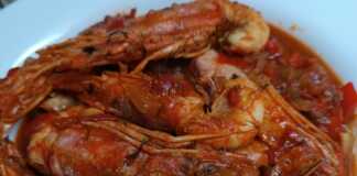 Ένα πιάτο με κόκκινες γαρίδες μέσα σε πλούσια, κόκκινη σάλτσα ντομάτας.