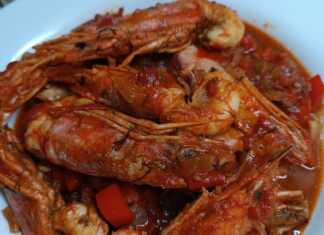 Ένα πιάτο με κόκκινες γαρίδες μέσα σε πλούσια, κόκκινη σάλτσα ντομάτας.