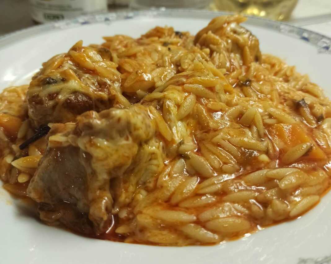 giouvetsi mosxari Μια γάστρα γεμάτη με ζεστό γιουβέτσι μοσχαράκι, με κόκκινη σάλτσα, κριθαράκι και λιωμένο τριμμένο τυρί στην επιφάνεια.