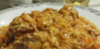 Μια γάστρα γεμάτη με ζεστό γιουβέτσι μοσχαράκι, με κόκκινη σάλτσα, κριθαράκι και λιωμένο τριμμένο τυρί στην επιφάνεια.