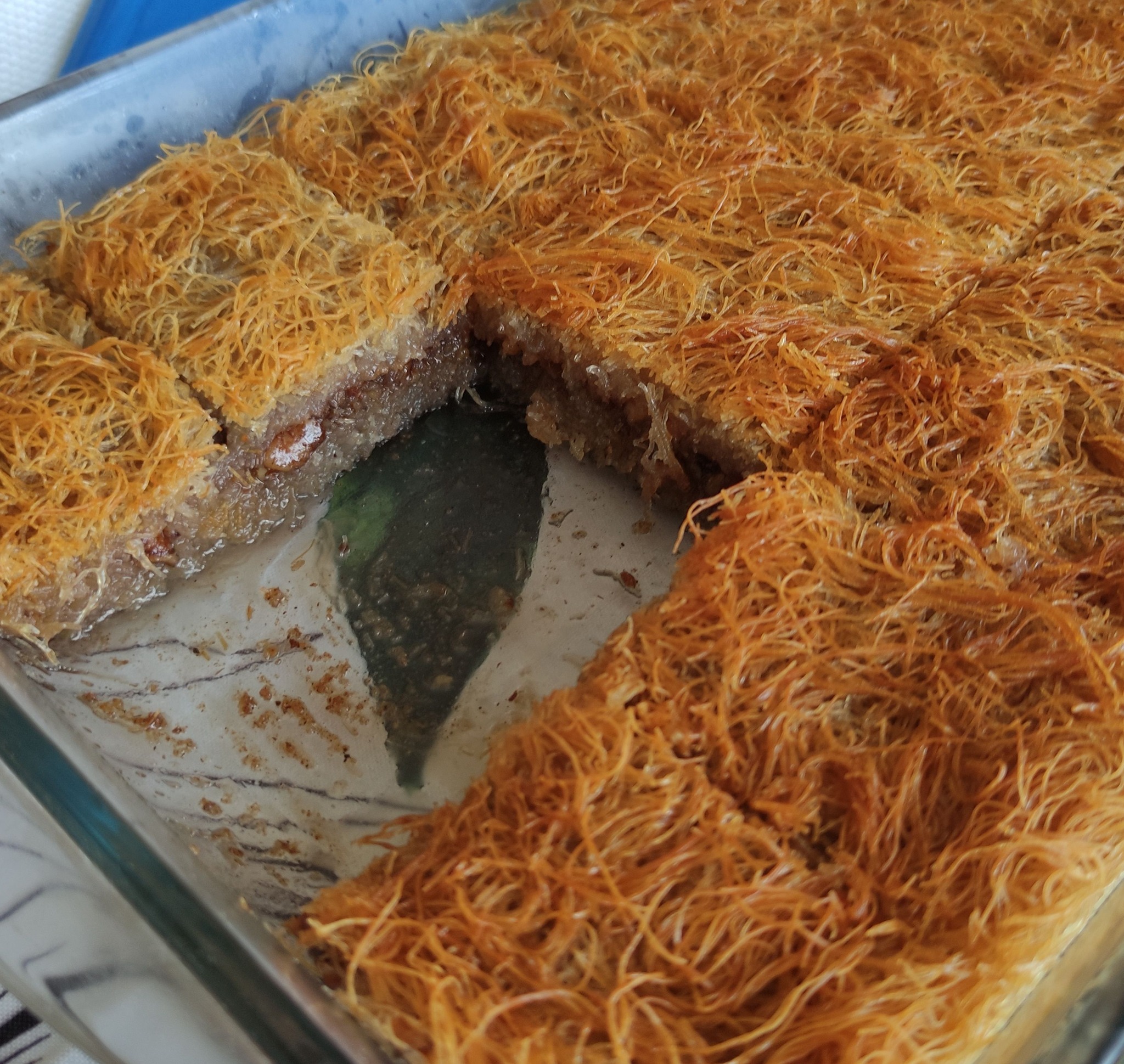 Ένα ταψί γεμάτο χρυσαφένιο, σιροπιασμένο κανταΐφι, πασπαλισμένο με τριμμένο καρύδι και κανέλα.