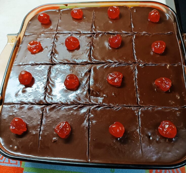 Ένα πυρέξ λαχταριστή, σιροπιασμένη καρυδόπιτα με καρύδια, καλυμμένη με ένα γυαλιστερό, σκούρο σοκολατένιο γλάσο.