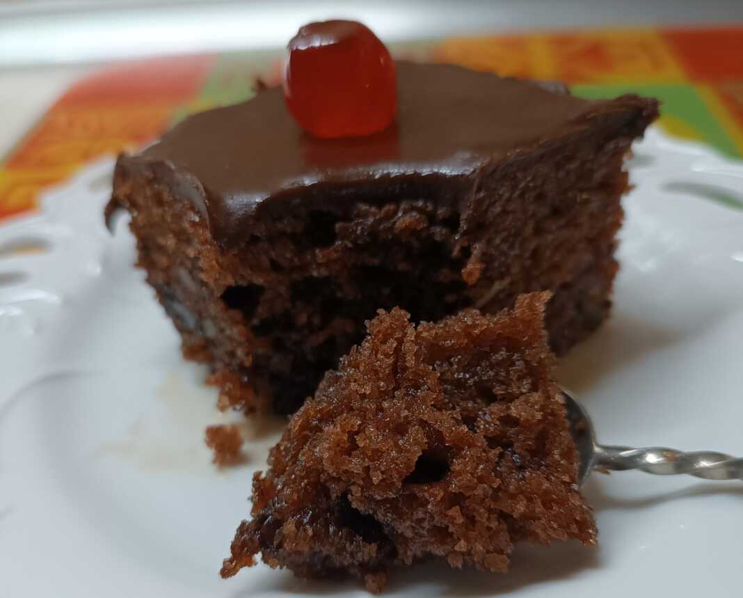 karidopita me sokolata1 Ένα τετράγωνο κομμάτι από λαχταριστή, σιροπιασμένη καρυδόπιτα με καρύδια, καλυμμένη με ένα γυαλιστερό, σκούρο σοκολατένιο γλάσο.