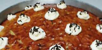 Ένα ταψί καρυδόπιτας με τρούφα, περιχυμένο με σιρόπι. Φαίνεται η αφράτη υφή του κέικ και τα κομμάτια καρυδιού.