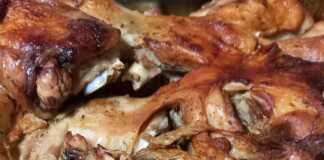 Ένα ταψί με ψητό κατσικάκι πάνω σε σχάρα, με ροδισμένες πατάτες από κάτω, έτοιμο να σερβιριστεί.