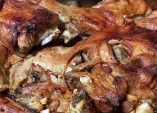 Ένα ταψί με ψητό κατσικάκι πάνω σε σχάρα, με ροδισμένες πατάτες από κάτω, έτοιμο να σερβιριστεί.