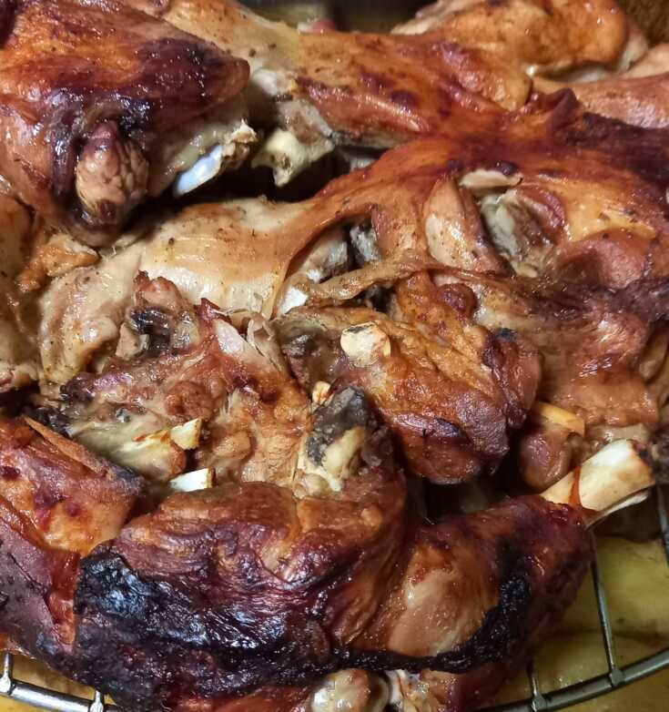 Ένα ταψί με ψητό κατσικάκι πάνω σε σχάρα, με ροδισμένες πατάτες από κάτω, έτοιμο να σερβιριστεί.