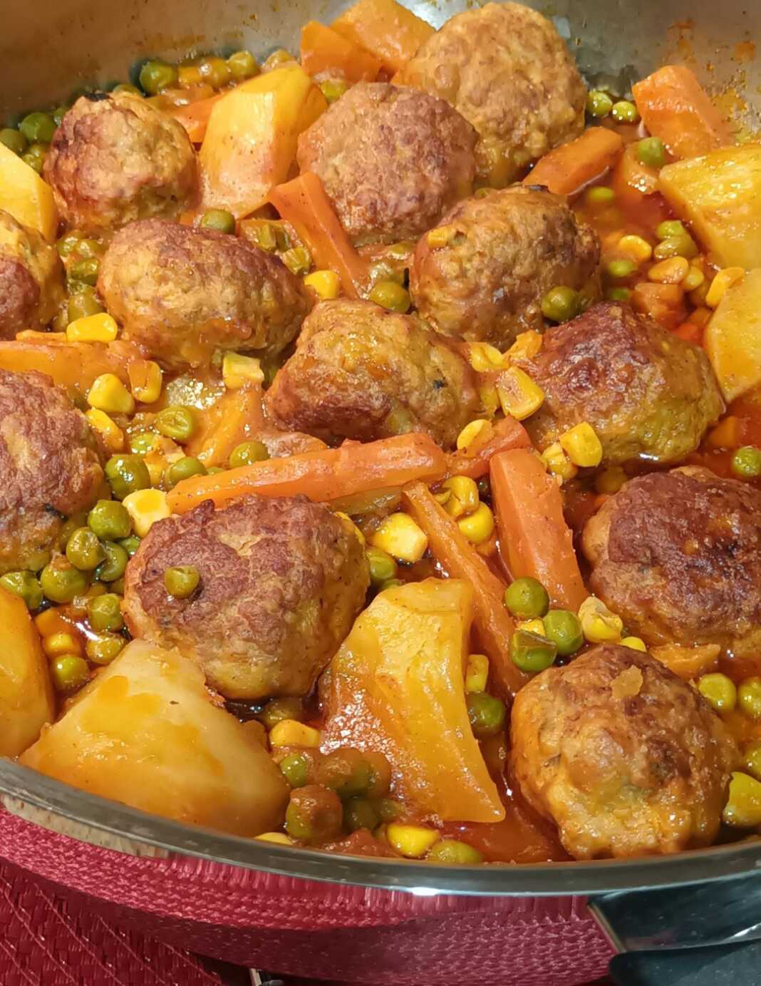 Ένα πυρεξ με κεφτεδάκια κατσαρόλας μέσα σε πλούσια κόκκινη σάλτσα με κομμάτια καρότου, πατάτας, πιπεριάς και καλαμποκιού, πασπαλισμένα με φρέσκο μαϊντανό.
