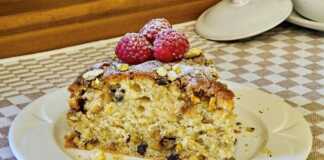 Ένα κομμάτι από ένα πλούσιο κέικ με επικάλυψη crumble και φιστίκια, τοποθετημένο σε ένα πιάτο.