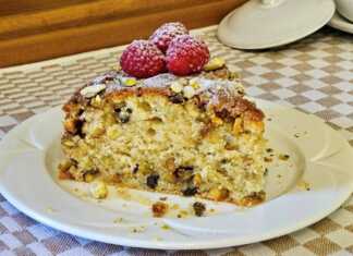 Ένα κομμάτι από ένα πλούσιο κέικ με επικάλυψη crumble και φιστίκια, τοποθετημένο σε ένα πιάτο.