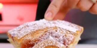 Αφράτο, χρυσαφένιο κέικ με μαρμελάδα φράουλας σε σπείρα στην επιφάνεια, πασπαλισμένο με ζάχαρη άχνη, κομμένο σε φέτες.