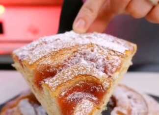 Αφράτο, χρυσαφένιο κέικ με μαρμελάδα φράουλας σε σπείρα στην επιφάνεια, πασπαλισμένο με ζάχαρη άχνη, κομμένο σε φέτες.