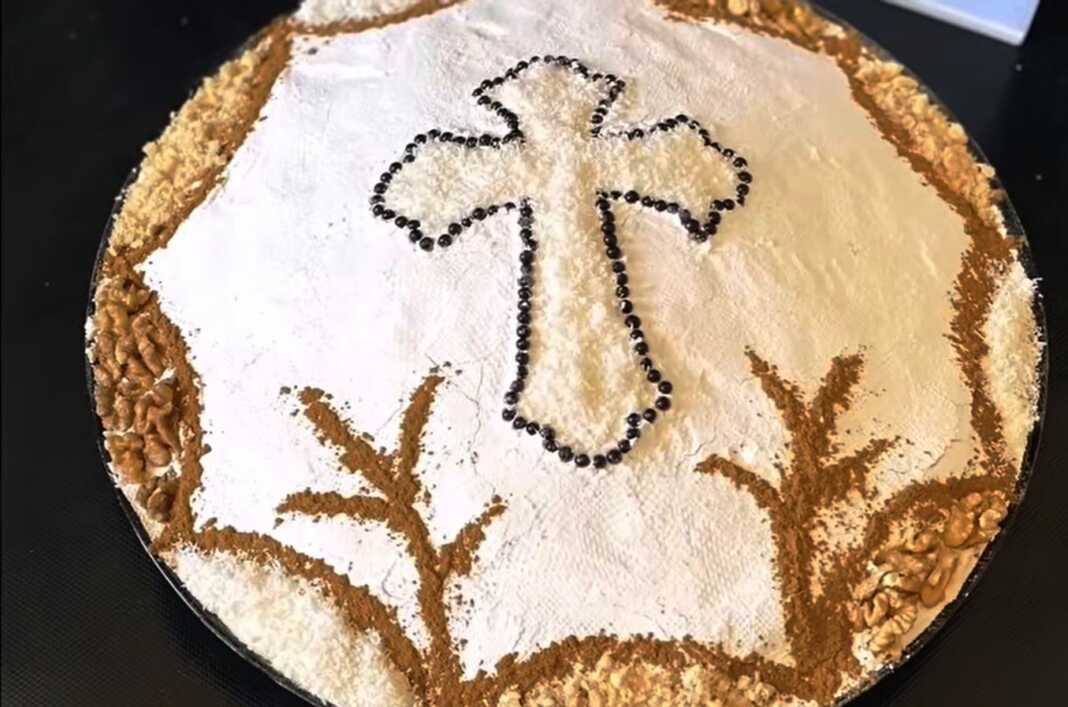 Ένα πιάτο με στολισμένα κόλλυβα, καλυμμένα με ζάχαρη άχνη και διακοσμημένα με σταυρό από τριμμένη καρύδα, κανέλα και βρώσιμες πέρλες.