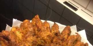 Ένα πιάτο γεμάτο χρυσαφένιους, τηγανητούς κολοκυθοκεφτέδες, γαρνιρισμένους με φρέσκα μυρωδικά.