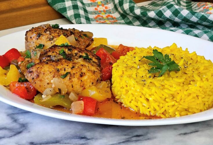 Πιάτο με ζουμερό κοτόπουλο με πιπεριές σε κόκκινη σάλτσα και αρωματικό ρύζι με σαφράν.