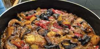 Λαχανικά Φούρνου με Αρωματική Σάλτσα Ένα ταψί με λαχταριστά ψητά λαχανικά, όπως μελιτζάνες, πιπεριές και πατάτες, μέσα σε κόκκινη σάλτσα, με φρέσκα βότανα από πάνω.