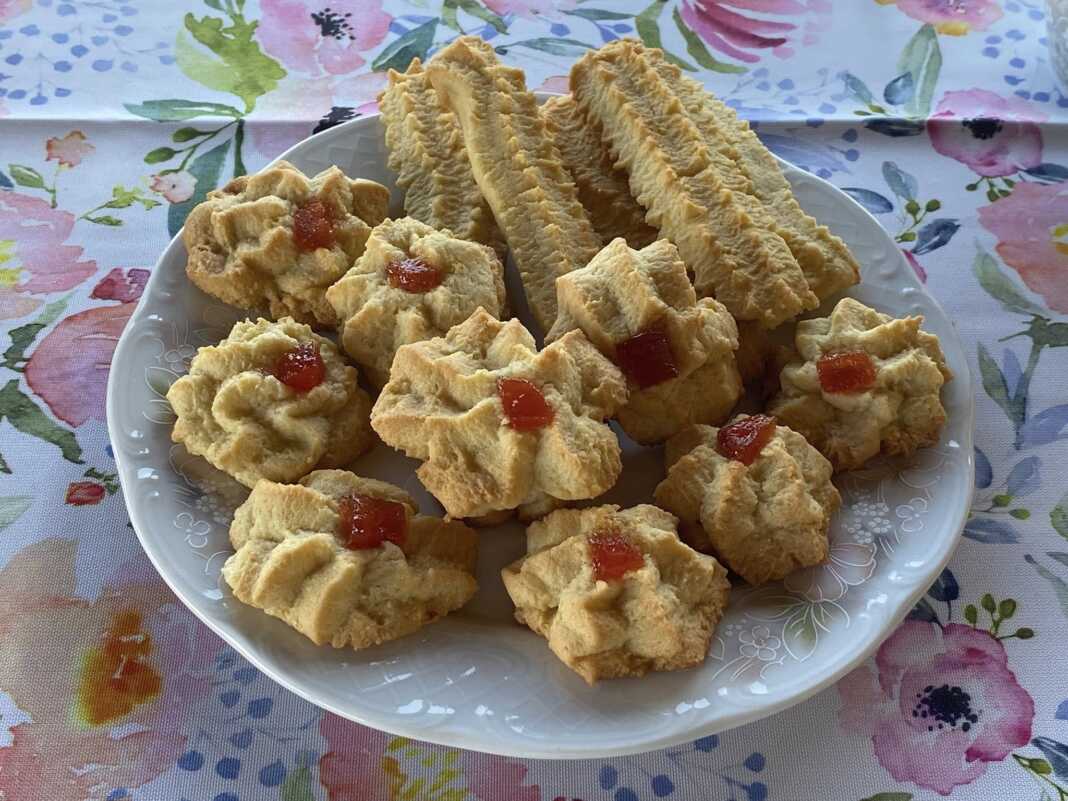 Μια συλλογή από στρογγυλά και ανθόσχημα μπισκοτάκια με λεμόνι, σε διάφορα μεγέθη, τοποθετημένα σε μια επιφάνεια.