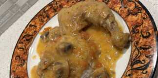 Κοτόπουλο Λεμονάτο στην Κατσαρόλα Ένα πιάτο με κοτόπουλο λεμονάτο, με πλούσια κίτρινη σάλτσα, κομμάτια μανιταριών και ρύζι μπασμάτι στο πλάι.