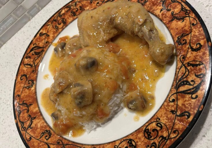 Ένα πιάτο με κοτόπουλο λεμονάτο, με πλούσια κίτρινη σάλτσα, κομμάτια μανιταριών και ρύζι μπασμάτι στο πλάι.