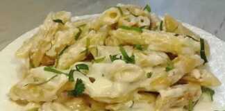 Ένα πιάτο γεμάτο με κρεμώδη, χρυσαφένια μακαρόνια, αναμεμειγμένα με λιωμένο τυρί, πασπαλισμένα με φρέσκο πράσινο μαϊντανό.