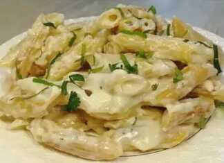 Ένα πιάτο γεμάτο με κρεμώδη, χρυσαφένια μακαρόνια, αναμεμειγμένα με λιωμένο τυρί, πασπαλισμένα με φρέσκο πράσινο μαϊντανό.