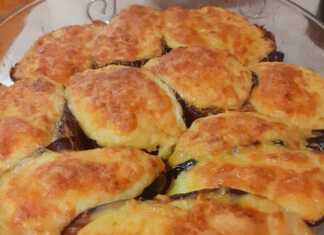 Ένα ταψί με γεμιστές μελιτζάνες σε σχήμα βαρκούλας, καλυμμένες με λευκή μπεσαμέλ και λίγο τριμμένο τυρί, ψημένες μέχρι να ροδίσουν.