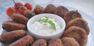 Πιάτο με χρυσαφένιους μελιτζανοκεφτέδες και ένα μπολάκι με δροσερή σως γιαουρτιού, γαρνιρισμένο με δυόσμο.