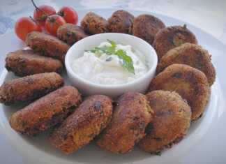 Πιάτο με χρυσαφένιους μελιτζανοκεφτέδες και ένα μπολάκι με δροσερή σως γιαουρτιού, γαρνιρισμένο με δυόσμο.