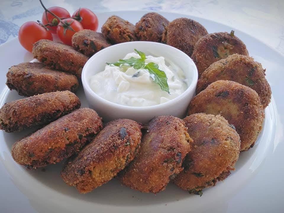 melitzanokeftedakia Πιάτο με χρυσαφένιους μελιτζανοκεφτέδες και ένα μπολάκι με δροσερή σως γιαουρτιού, γαρνιρισμένο με δυόσμο.