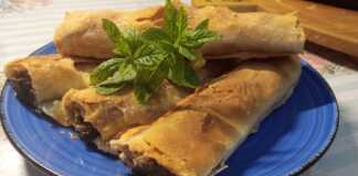 Ένα πιάτο με χρυσαφένια, ρολαριστά κομμάτια μελιτζανόπιτας με χειροποίητο φύλλο.