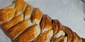 Ένα οβάλ γλυκό ψωμί με γέμιση πραλίνας και ξηρών καρπών, διακοσμημένο με περίτεχνο σχέδιο από στριμμένες λωρίδες ζύμης.