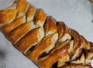 Ένα οβάλ γλυκό ψωμί με γέμιση πραλίνας και ξηρών καρπών, διακοσμημένο με περίτεχνο σχέδιο από στριμμένες λωρίδες ζύμης.