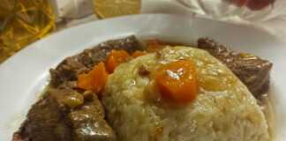 Ένα πιάτο με μαγειρεμένο μοσχάρι σε κομμάτια, περιχυμένο με μια πηχτή, καστανή σάλτσα, δίπλα σε ένα πιάτο με αφράτο πιλάφι.