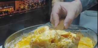 Ένα ορθογώνιο ταψί με ψημένο μπακαλιάρο καλυμμένο με ροδισμένα λαχανικά και λιωμένο, χρυσαφένιο τυρί.