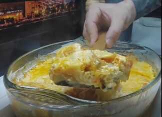 Ένα ορθογώνιο ταψί με ψημένο μπακαλιάρο καλυμμένο με ροδισμένα λαχανικά και λιωμένο, χρυσαφένιο τυρί.